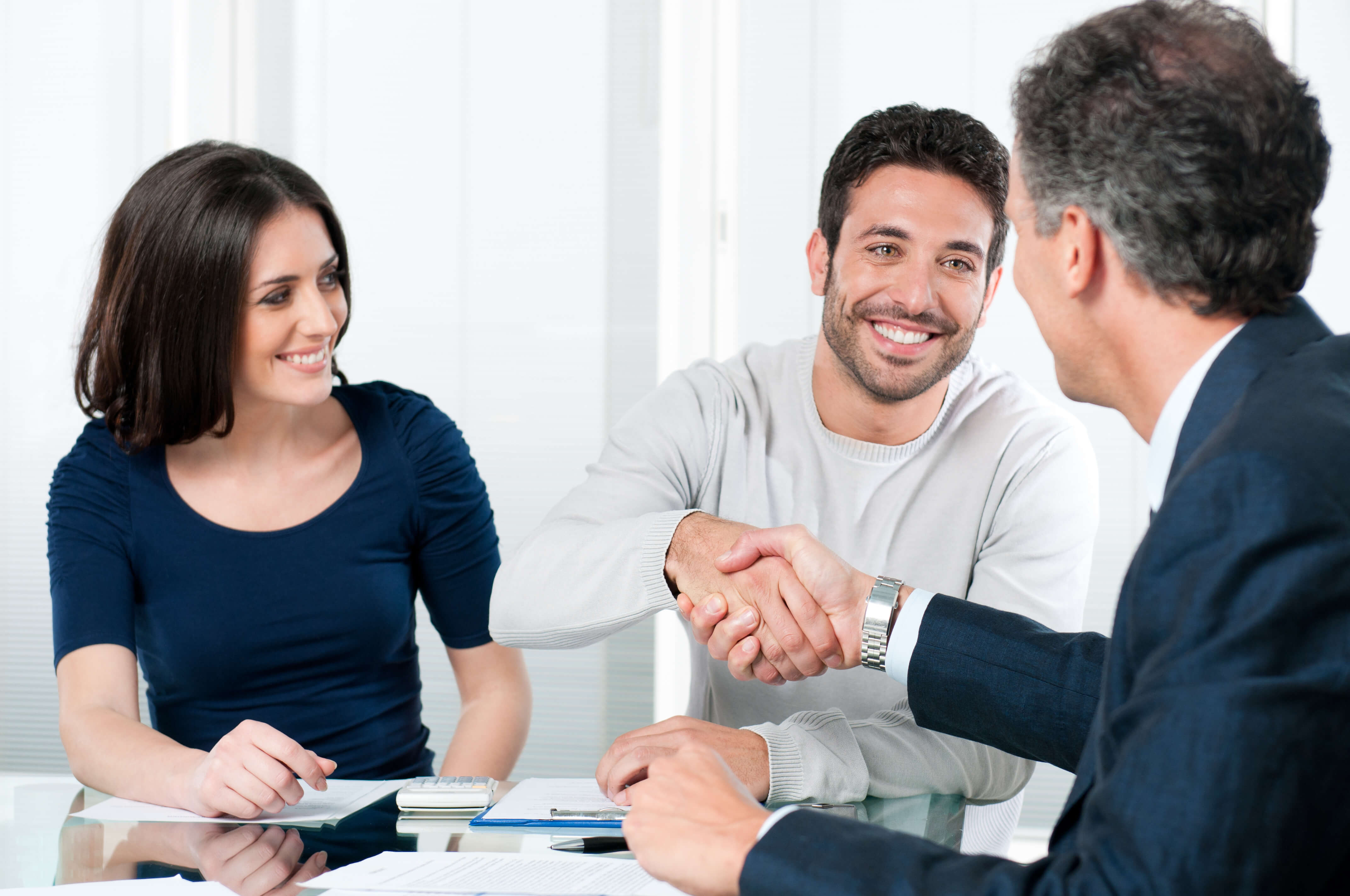 Couple smiling while husband shakes the lawyer's hand 